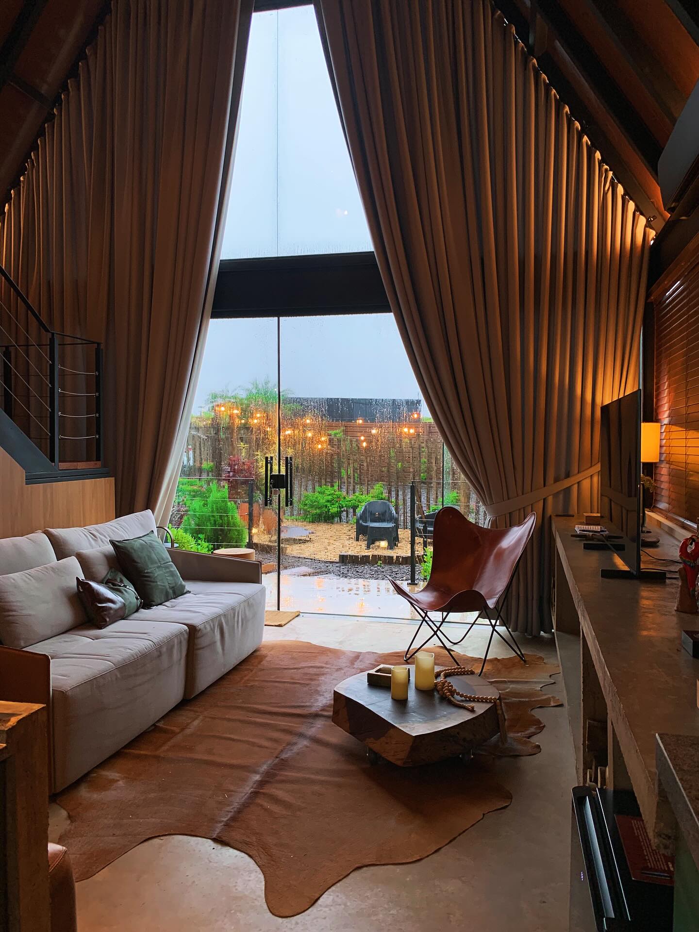 Sala com sofá e ampla janela triangular do chalé